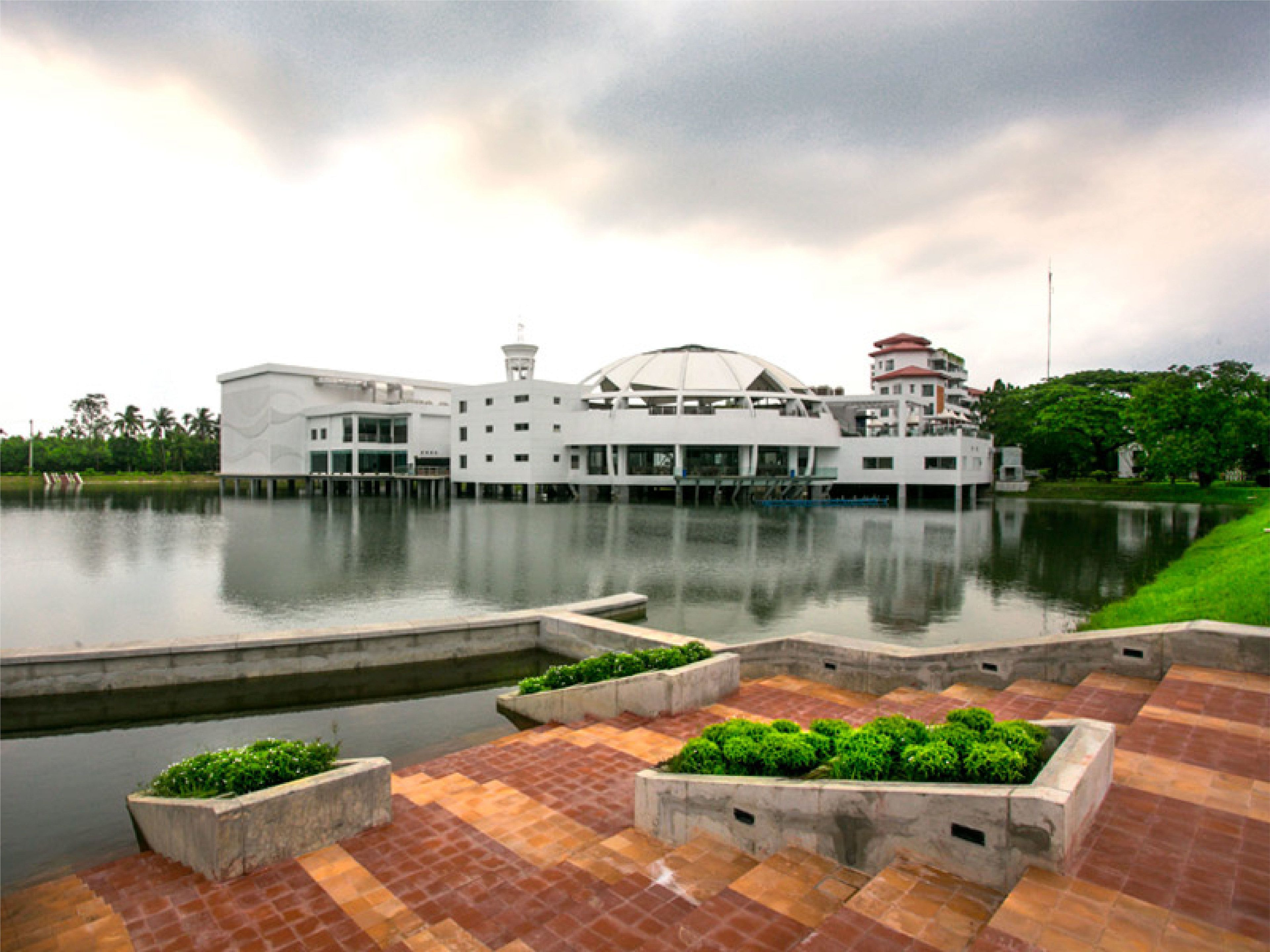 A waterfront hotel with a modern design, featuring a central dome structure and multiple levels.