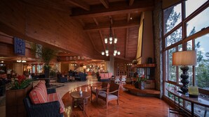 A spacious lobby with wooden floors, a large seating area, and a view of the outdoors through large windows.