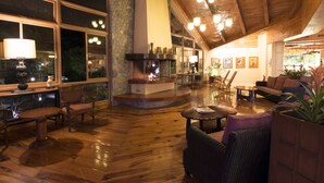 A spacious living area with a fireplace, wooden flooring, and large windows.