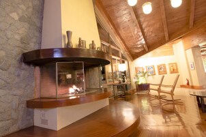A stone wall, a fireplace with a glass enclosure, wooden flooring, and a wooden ceiling.