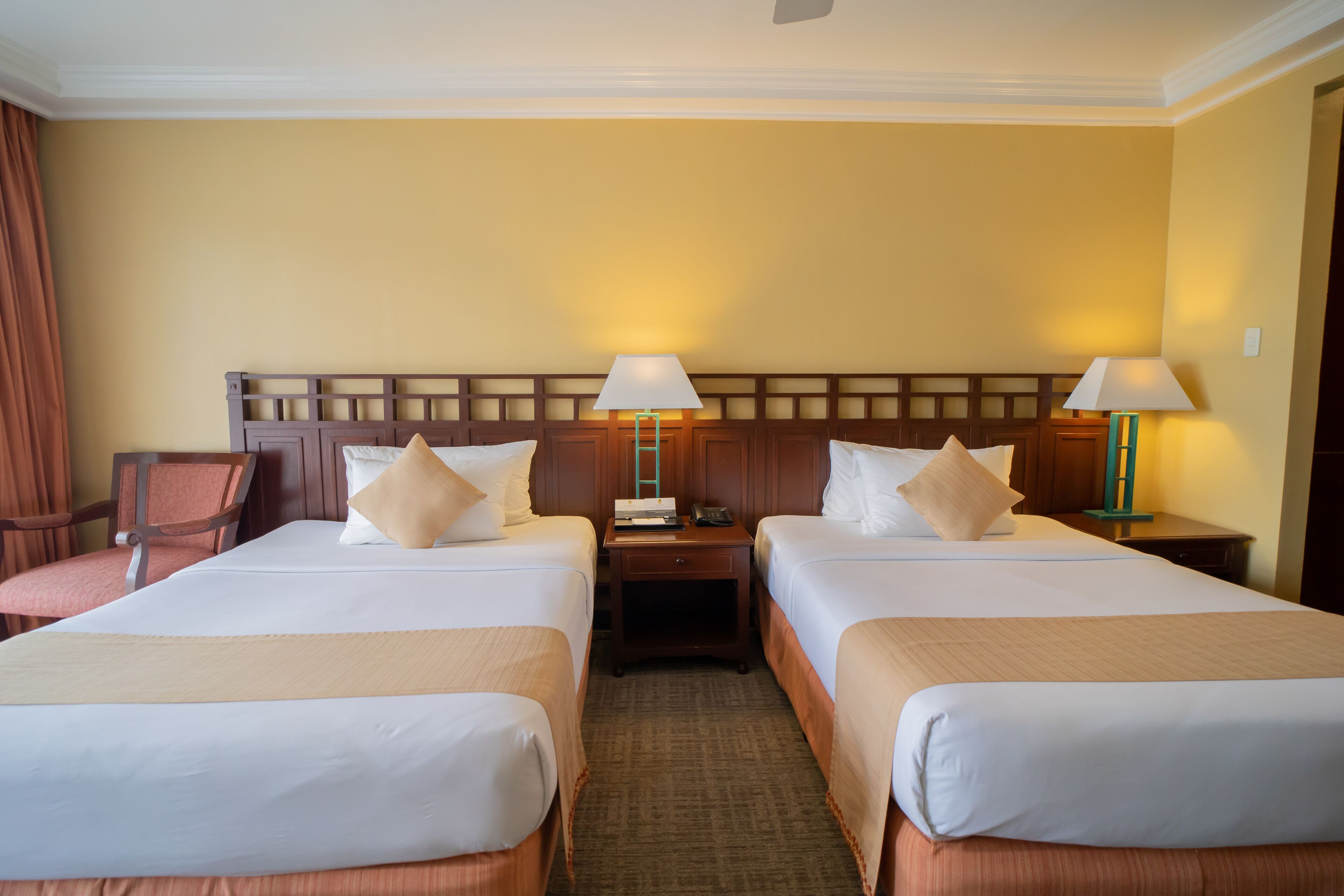 Een hotelkamer met twee bedden, een nachtkastje, een stoel en een lamp.