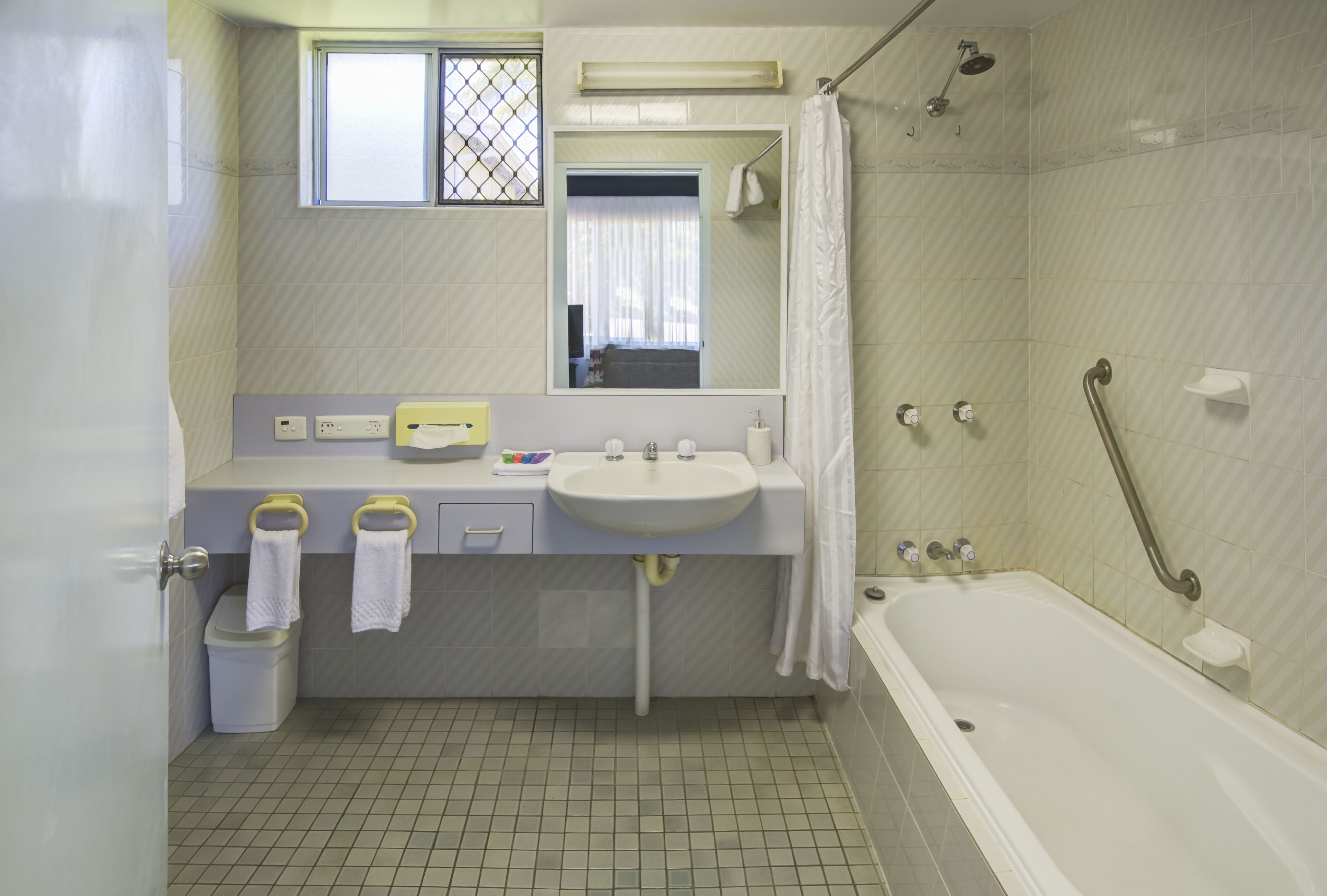 A bathroom with a sink, mirror, and bathtub.