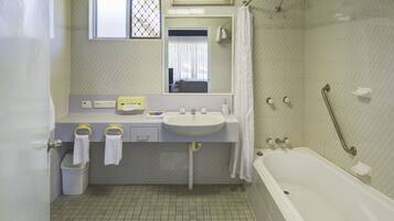 A bathroom with a sink, mirror, and bathtub.