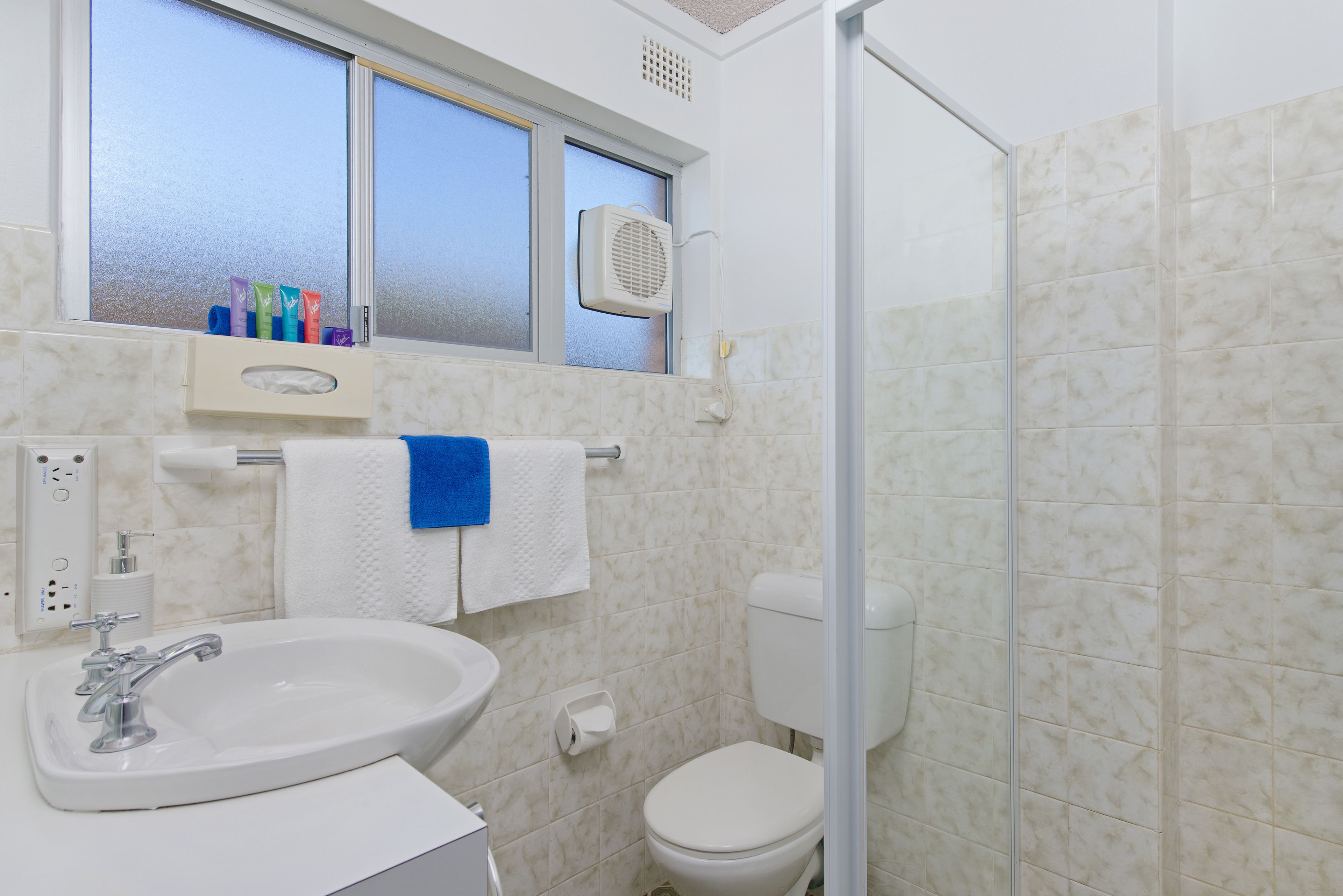 A bathroom with a sink, toilet, and window.