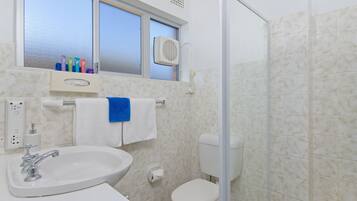 A bathroom with a sink, toilet, and window.