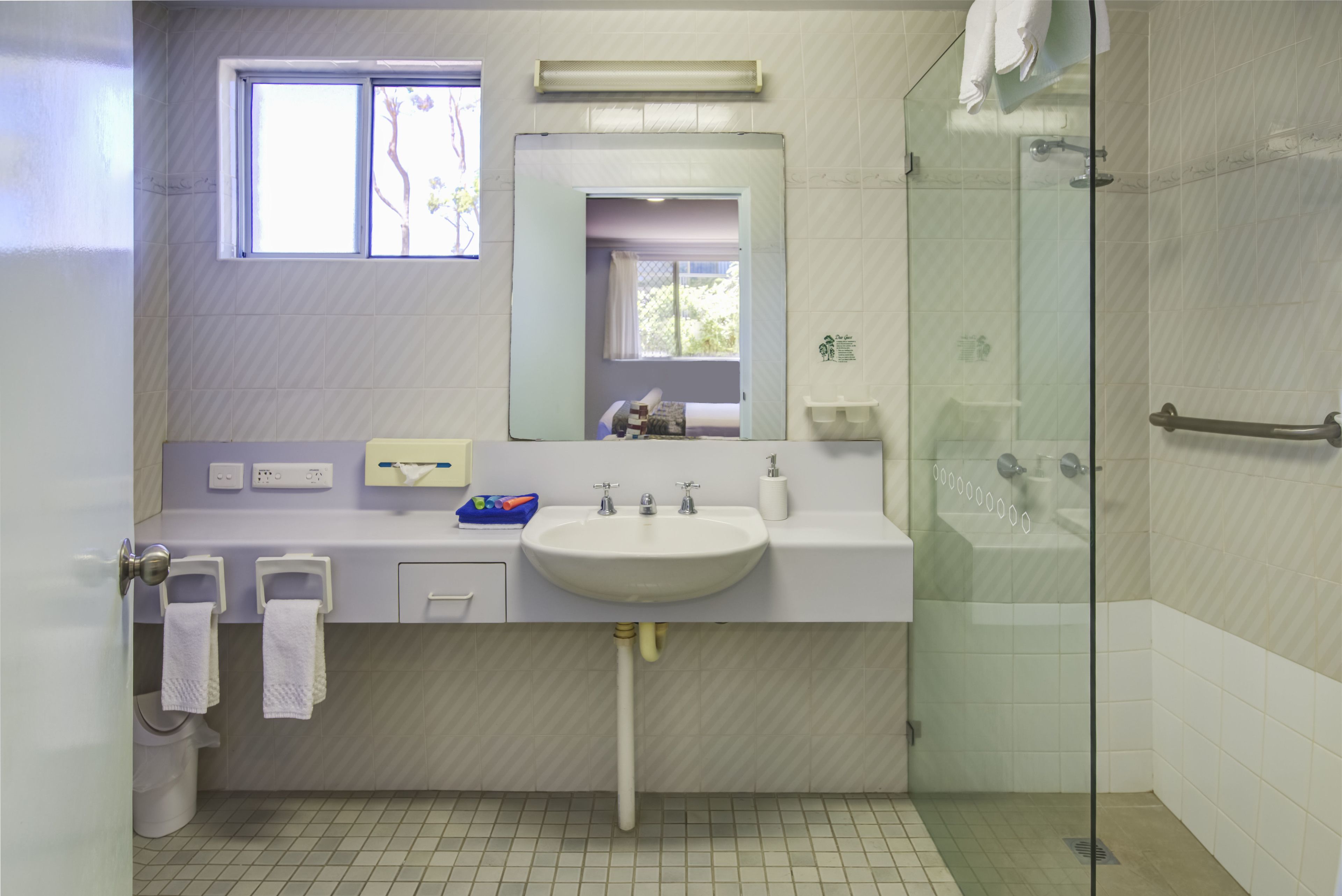 Een badkamer met een wastafel, spiegel en douche.