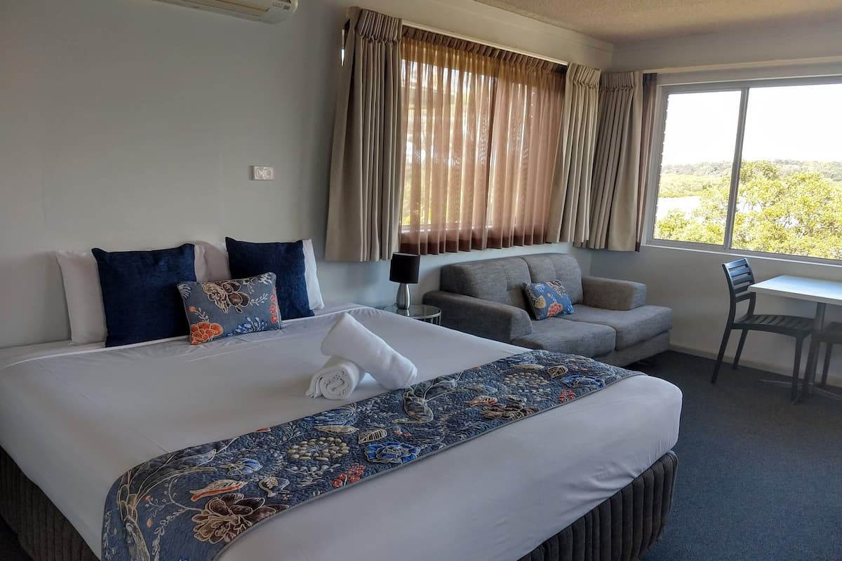 A hotel room with a large bed, a sofa, a desk, and a chair.