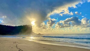 Una playa con cielo despejado y luz de sol.