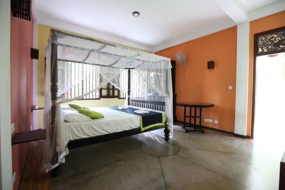 Un dormitorio con cama, mesita de noche y ventana con mosquitera.