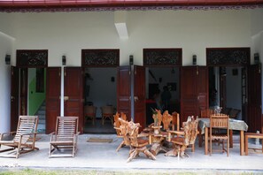 A wooden outdoor seating area with chairs and tables, a staircase, and a door leading inside.