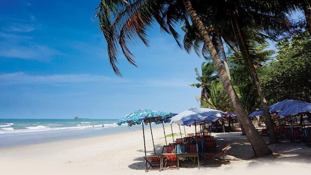 A beach with palm trees, umbrellas, and beach chairs. - New Paradise Home Resort (Rayong)