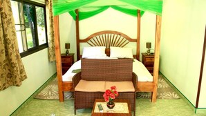 A room with a four-poster bed, a small table with a vase of flowers, and a window with curtains. - New Paradise Home Resort (Rayong)