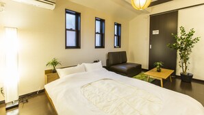 A hotel room with a bed, a chair, a small table, and two potted plants. - Kyo Oyado Kurakura (Kyoto)