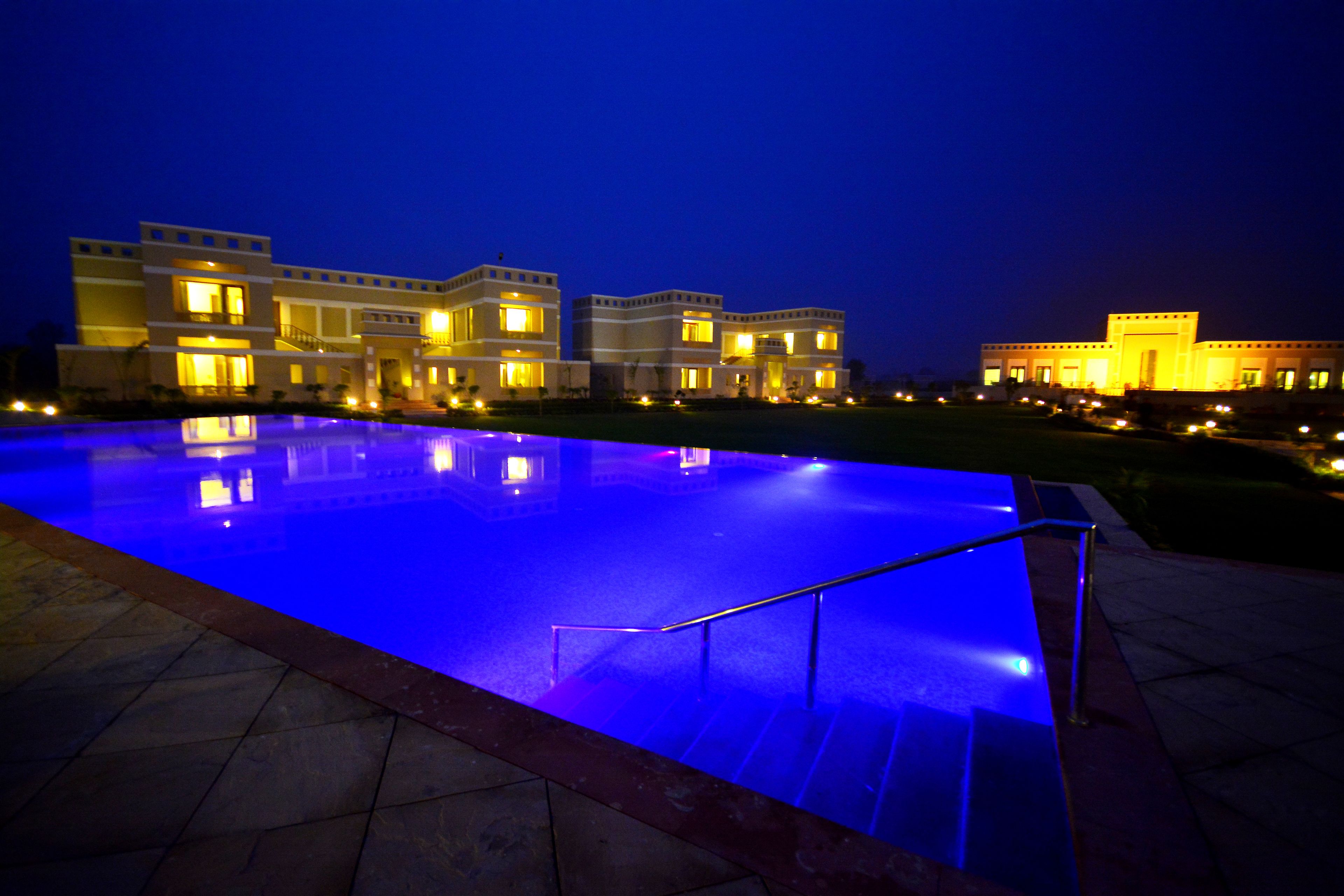 A modern hotel with a swimming pool at night.