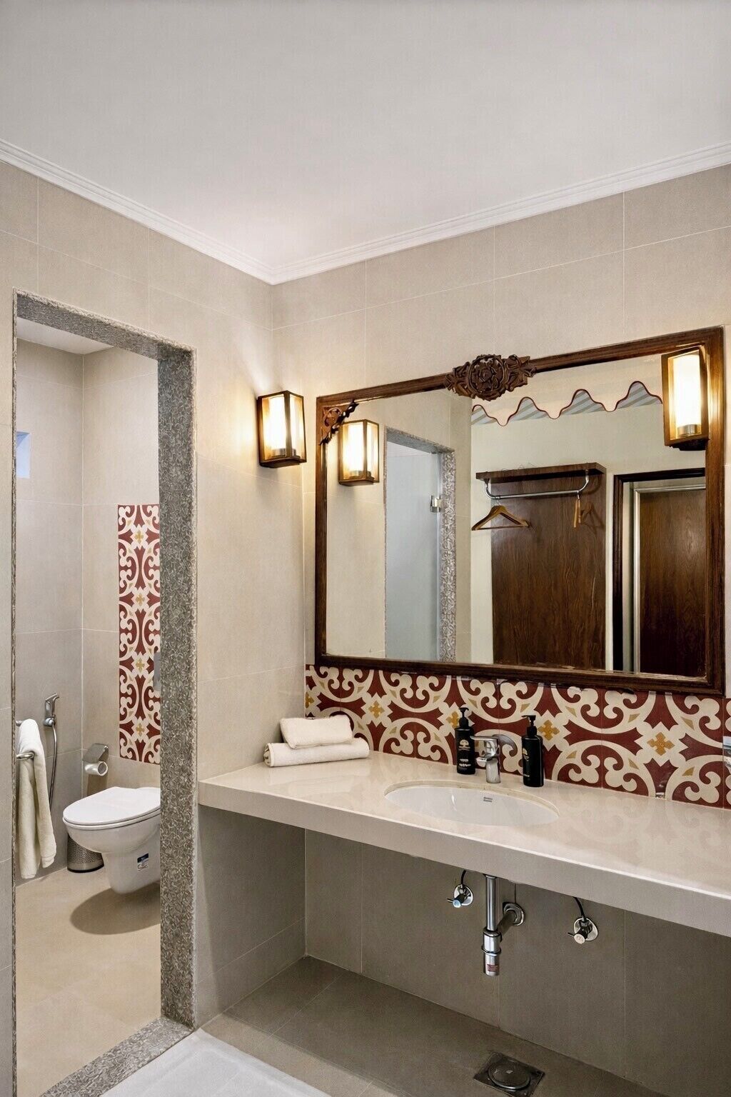 Uma casa de banho moderna com um espelho grande, duas luzes embutidas, um porta-toalhas e uma sanita.