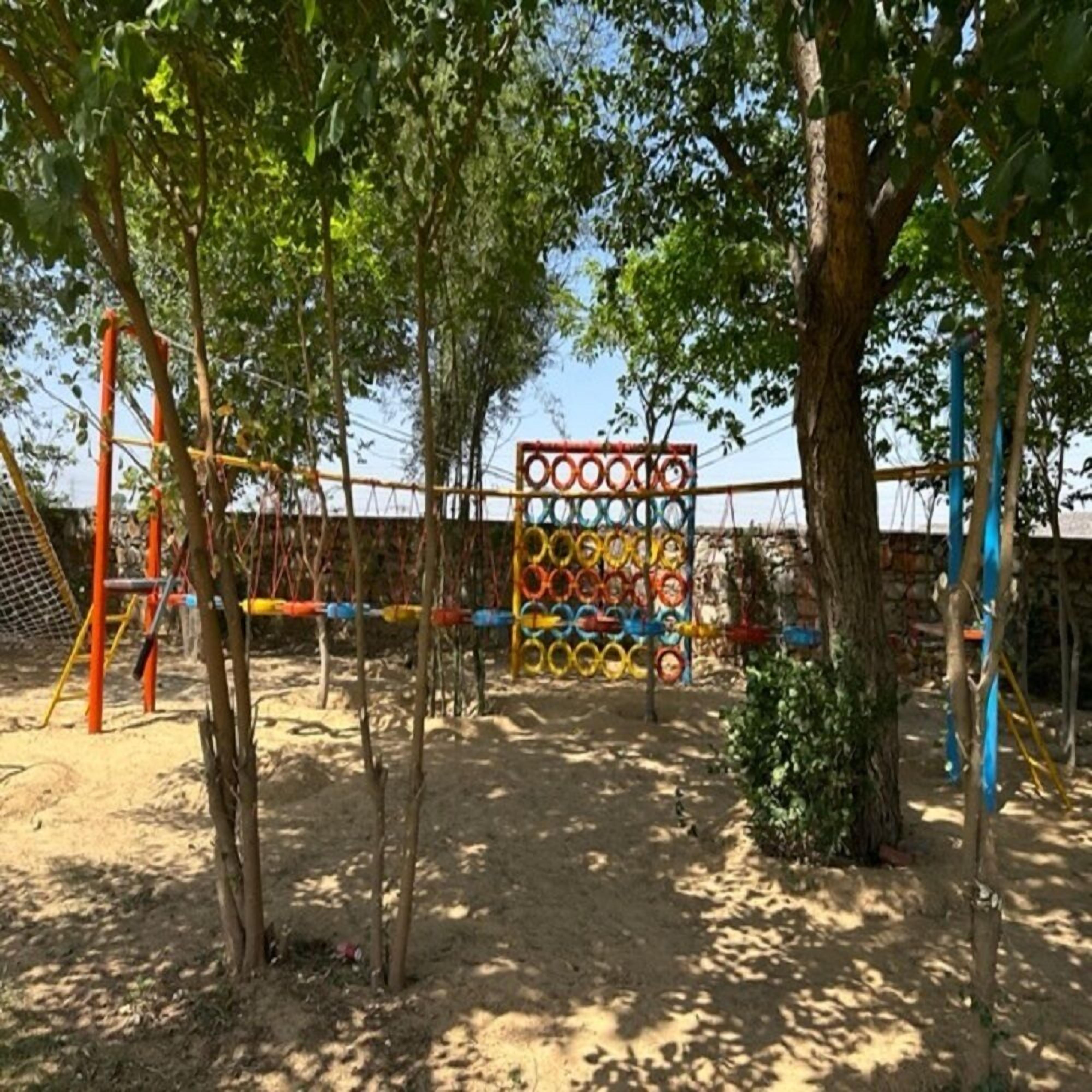 A playground with a climbing structure, swings, and a sand area.
