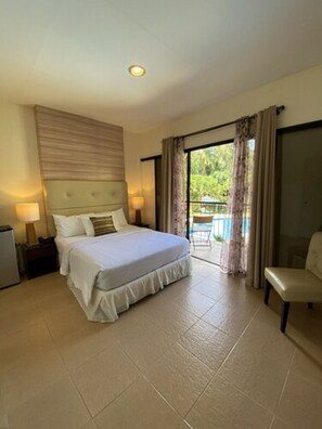 A hotel room with a bed, a chair, a desk, and a view of the outdoors.