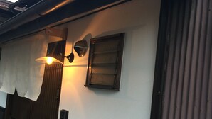 A room with a wooden door, a white wall, and a window with a dark frame.