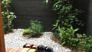 A garden area with a wooden deck, a variety of green plants, and a gravel path.
