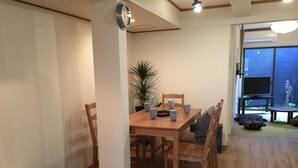 A dining area with a wooden table, chairs, and a clock on the wall.