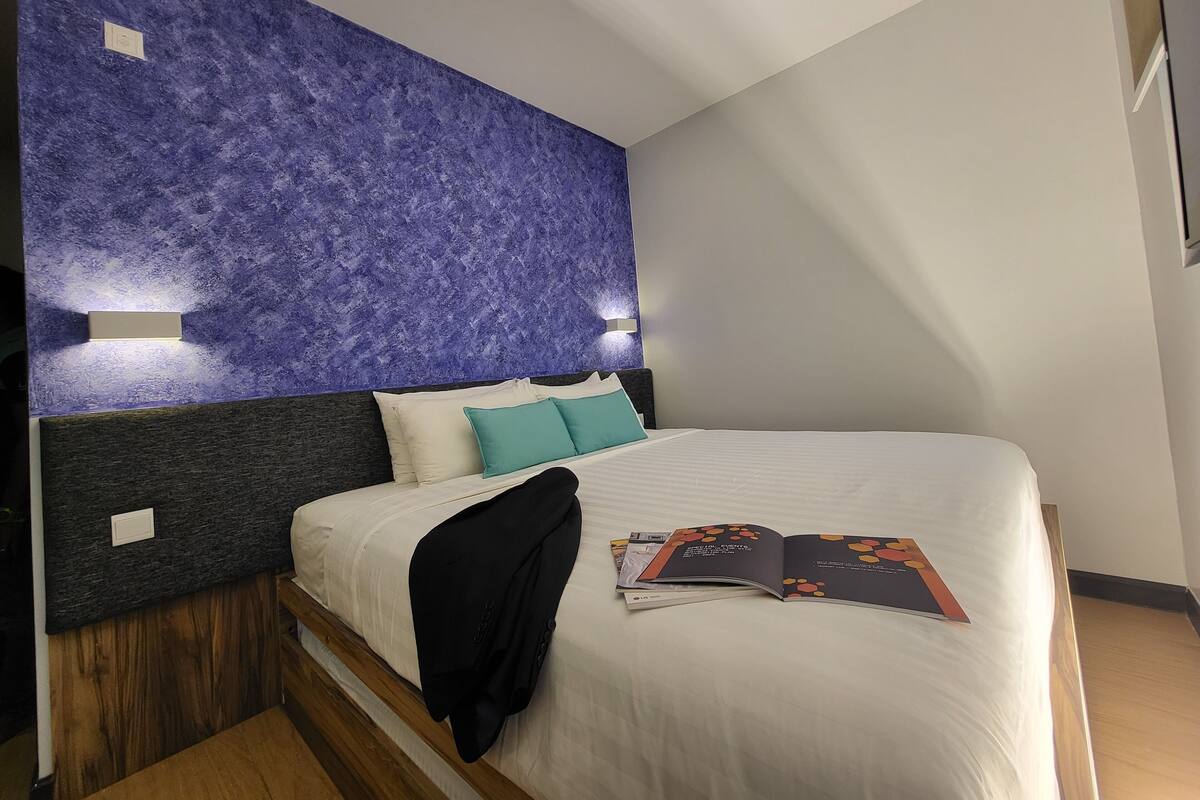 A modern bedroom with a bed, pillows, and a magazine on the bed.