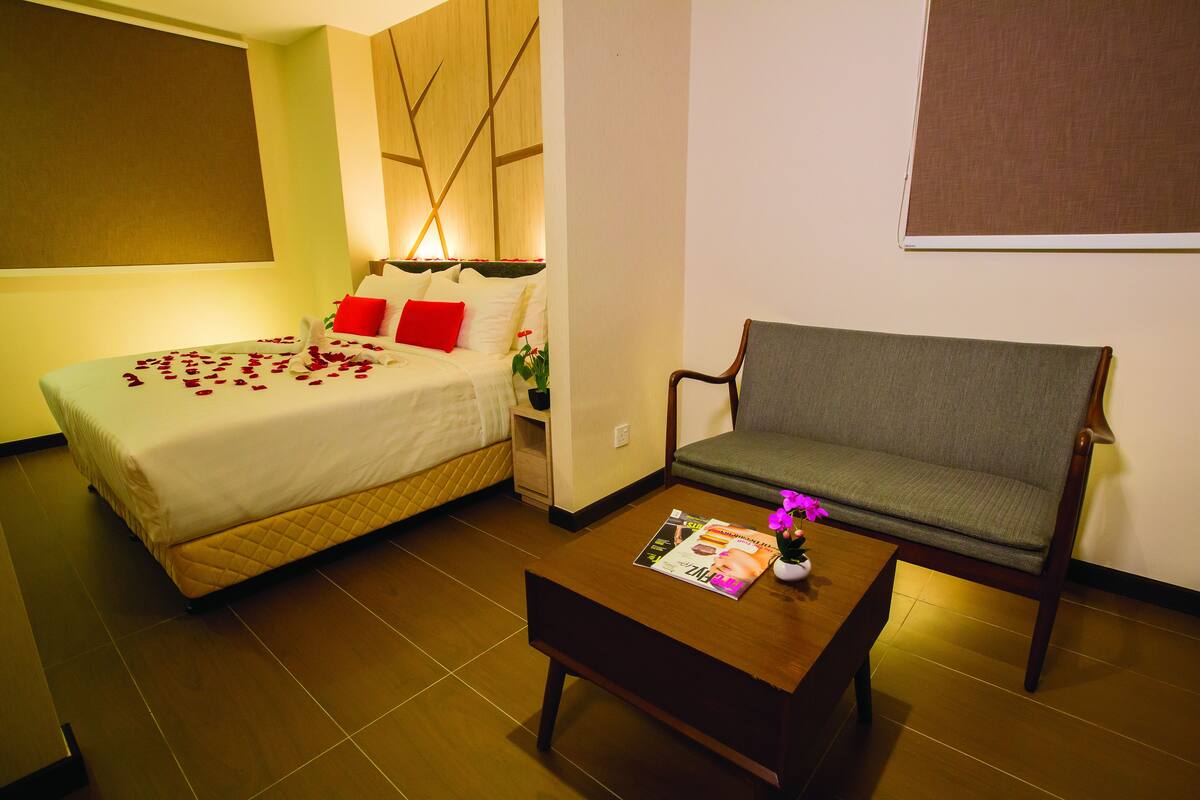 A hotel room with a bed, a sofa, a coffee table, and a magazine.