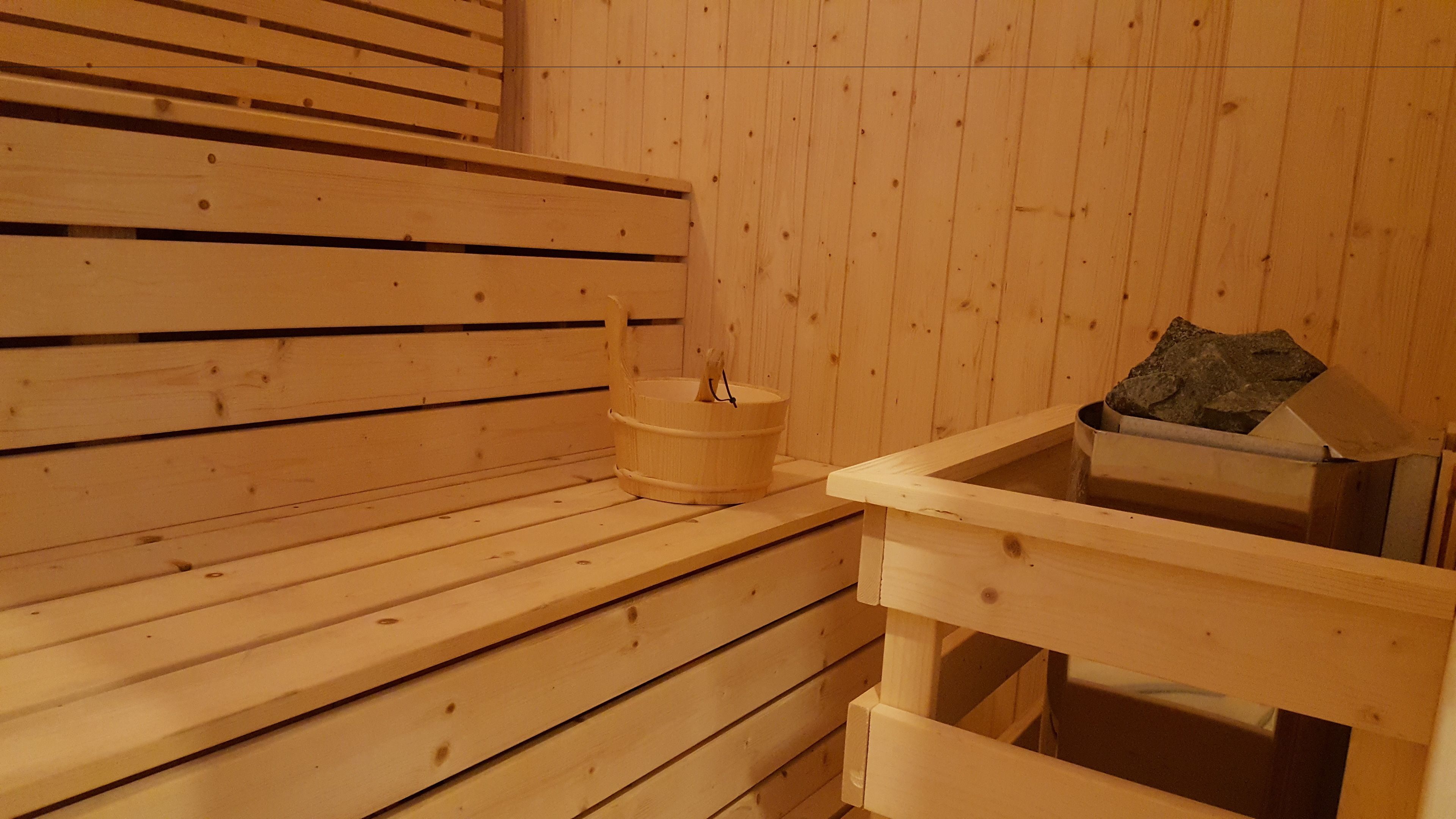 A wooden sauna with benches and a stone basin.