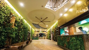 A hotel lobby with a ceiling fan, a reception desk, and a pathway leading to a water park area. - Grand Orient Hotel Perai (Perai)