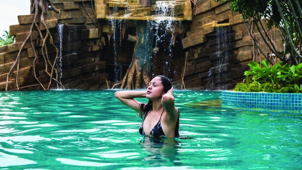 A woman in a swimming pool with a waterfall backdrop. - Grand Orient Hotel Perai (Perai)