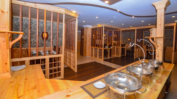 Una habitación tradicional japonesa con suelo de tatami, divisiones de madera y una zona de recepción con mostrador y fuentes de metal.