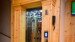 Un ascensor de madera con puerta de cristal, panel de control y pantalla de televisión.