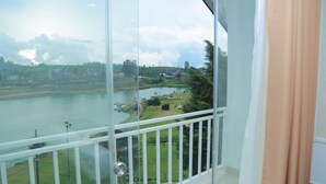 Un balcón con vista a un lago, edificios y follaje.