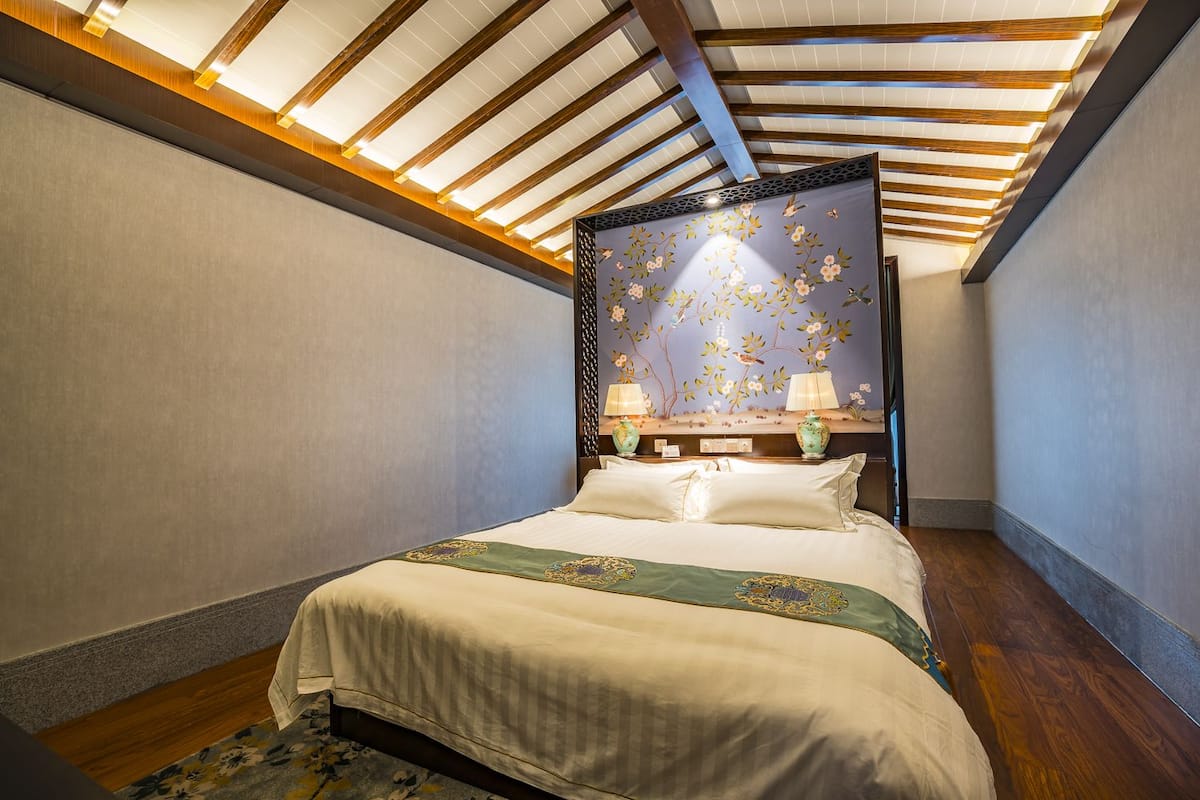 Un dormitorio con una cama grande, vigas de madera en el techo y un mural floral en la pared.