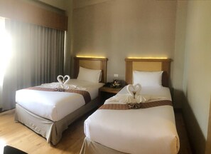 A hotel room with two beds, each adorned with a swan-shaped pillow and a brown decorative band. - D-ONE Hotel (Hat Yai)
