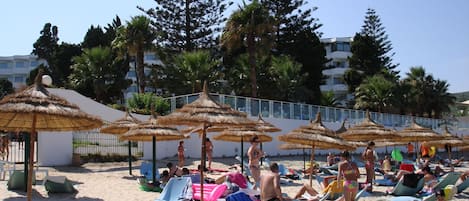 Am Strand, weißer Sandstrand, Liegestühle, Sonnenschirme