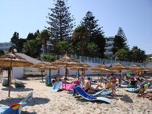 En la playa, arena blanca, sillas reclinables de playa, sombrillas