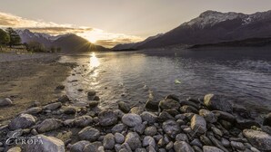A rocky lakeshore with a mountain backdrop and a visible hotel name. - Hotel Camping Europa (Domaso)
