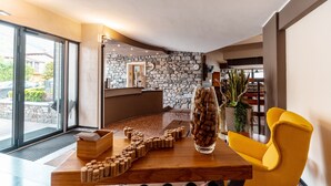 A modern interior with a wooden table, a yellow chair, and a stone wall. - Hotel Camping Europa (Domaso)