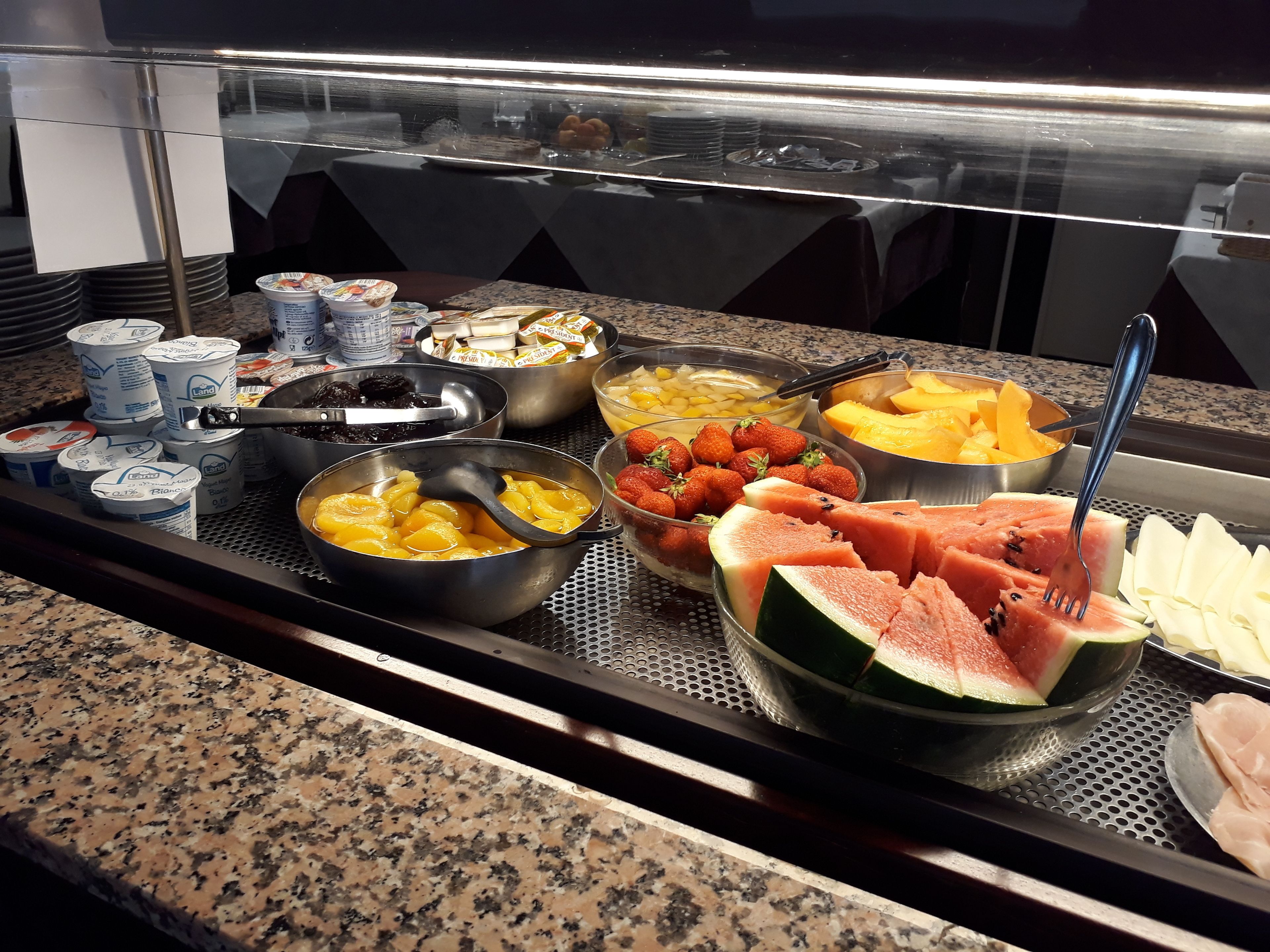 Ein Buffet mit verschiedenen Speisen, darunter Joghurt, Früchte und Käse.