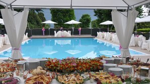 A poolside buffet with various food items and a pool in the background. - Hotel Camping Europa (Domaso)