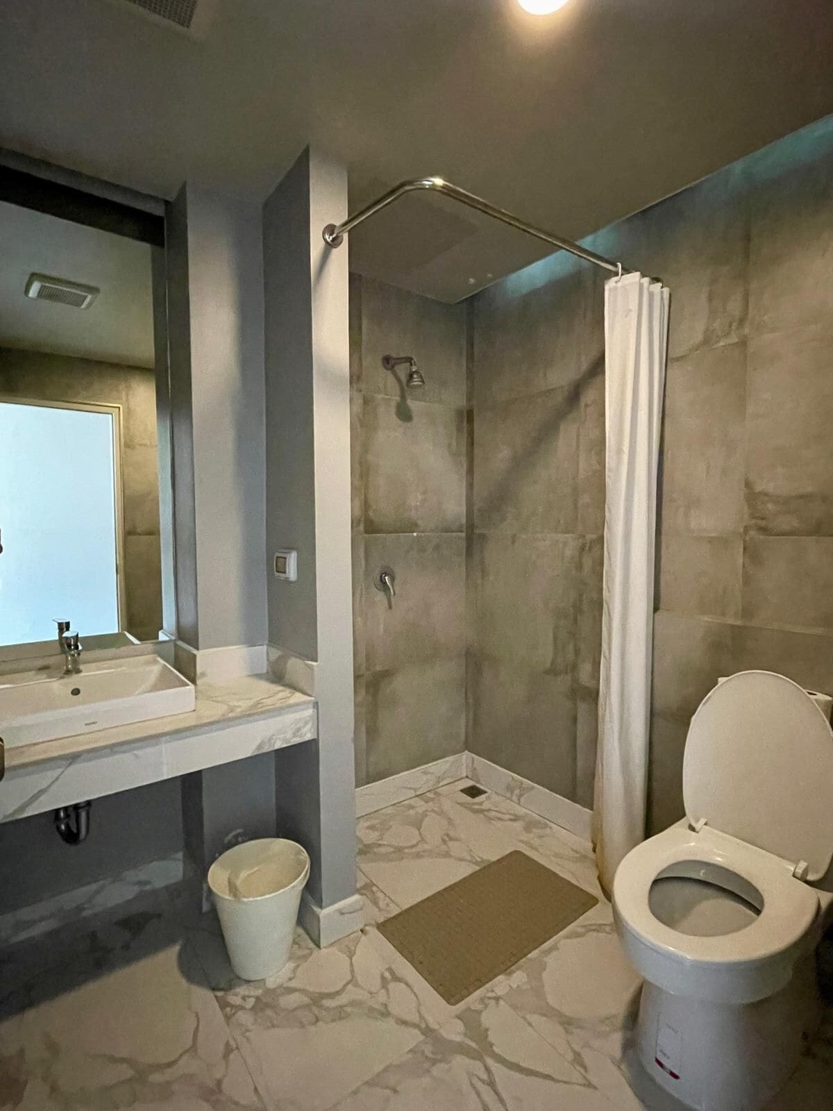 A modern bathroom with a shower, toilet, and sink.