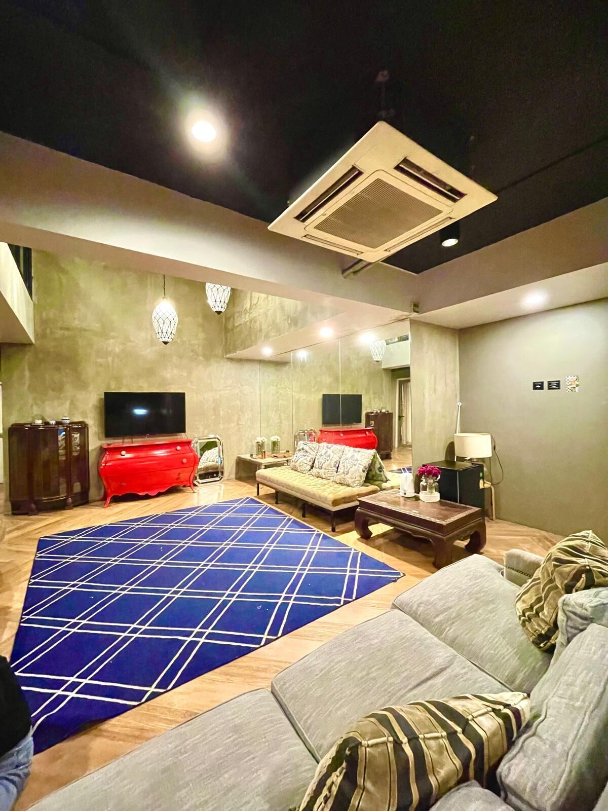 A living room with a blue patterned rug, a red entertainment unit, a sofa, a coffee table, and a television.