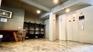 Un hall d’entrée spacieux avec un sol en marbre, un bureau en bois et des étagères pour exposer les chaussures.
