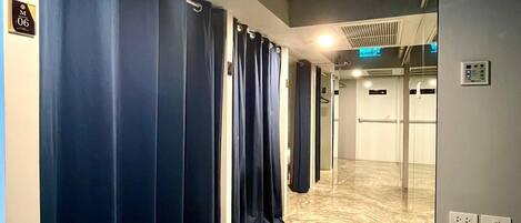 A hallway with blue curtains, a marble floor, and a ceiling vent.