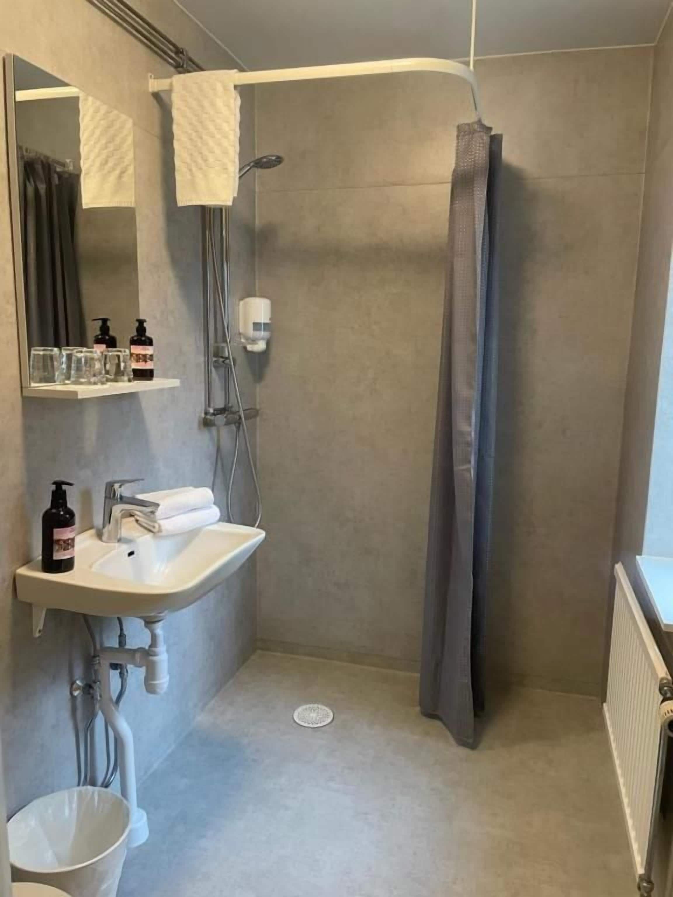 A bathroom with a shower, a sink, and a mirror.