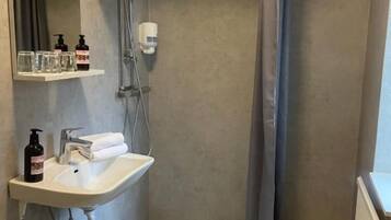 A bathroom with a shower, a sink, and a mirror.
