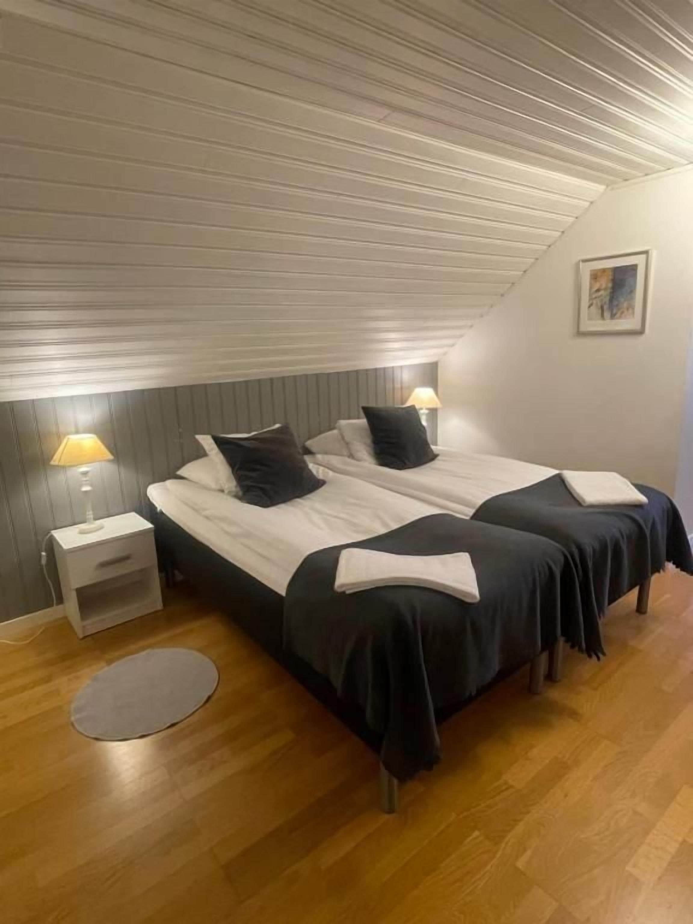 Ein Schlafzimmer mit zwei Betten, Holzboden und schräg versetzter Decke.