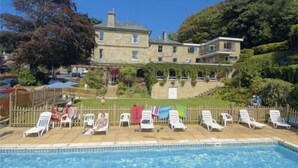 Una piscina con lettini e un grande edificio sullo sfondo.
