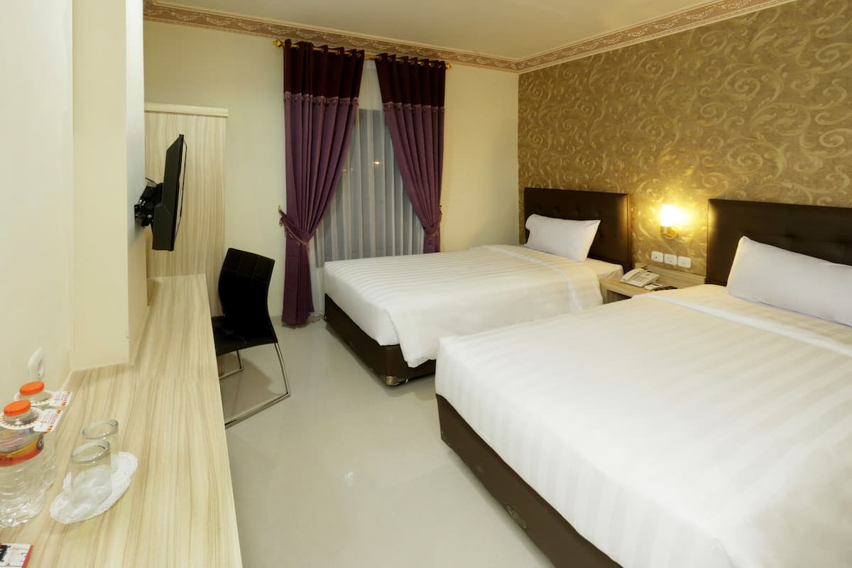 A hotel room with two beds, a desk with a chair, a television, and a window with curtains.
