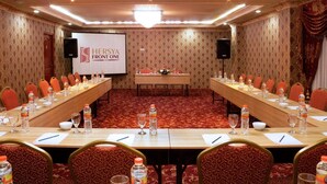 Una sala conferenze con un lungo tavolo, sedie e uno schermo proiettore che mostra "Hersya Front One".